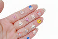 Small animal-themed nail art decorations on a hand with a colorful background
