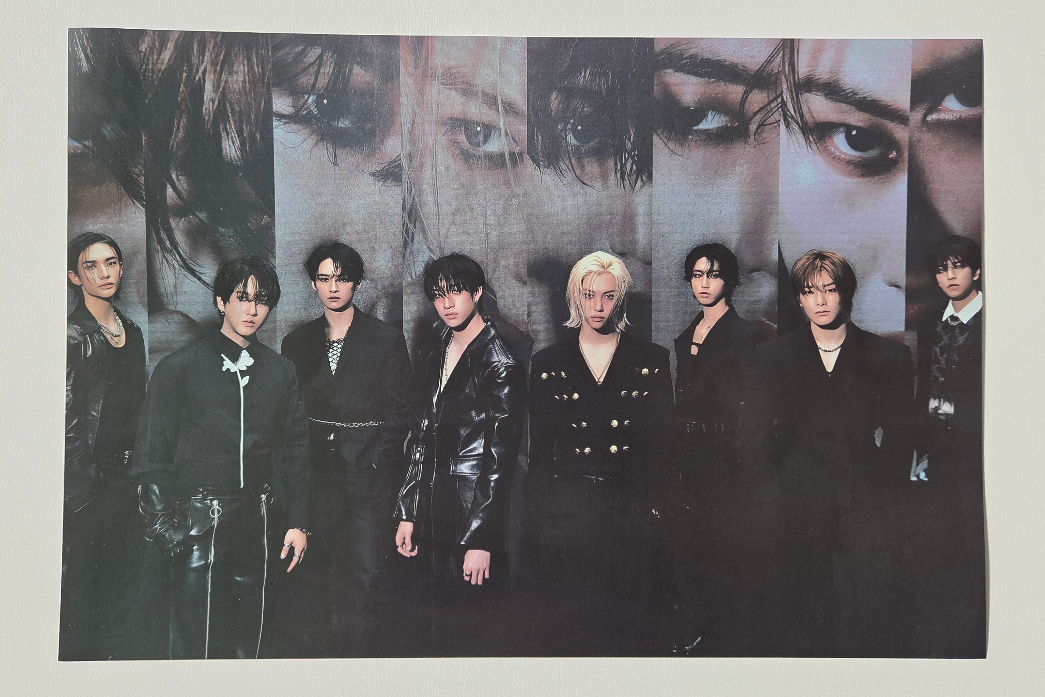Group of people in formal attire with a close-up of their faces on a poster.